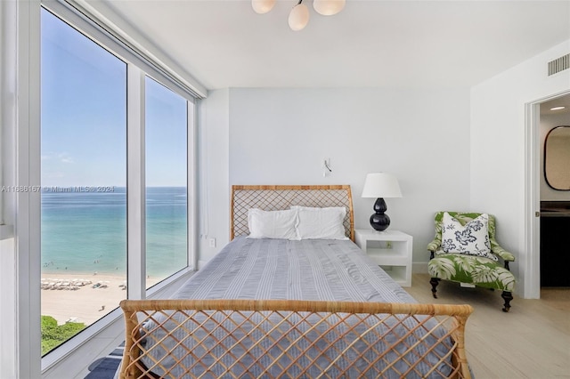 bedroom featuring a water view, a view of the beach, and carpet flooring