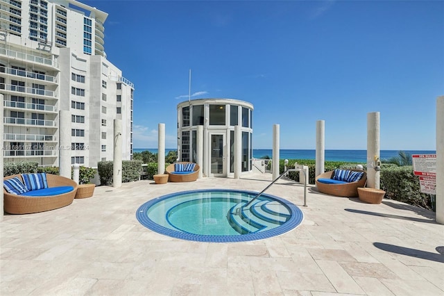 view of swimming pool with a hot tub, a patio area, and a water view