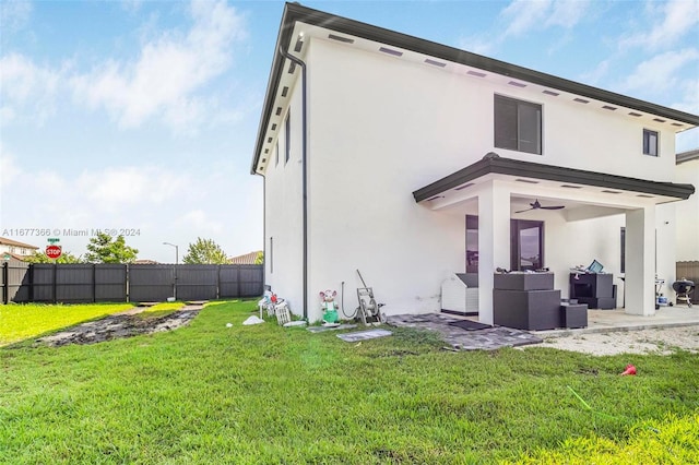 back of property with a patio, a yard, and ceiling fan