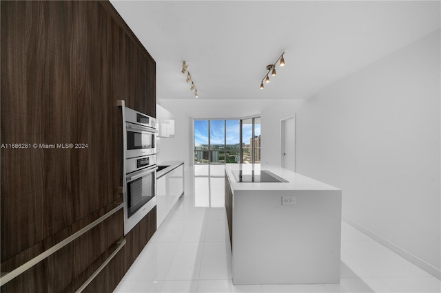 kitchen featuring black electric stovetop, a center island, rail lighting, and light tile patterned floors