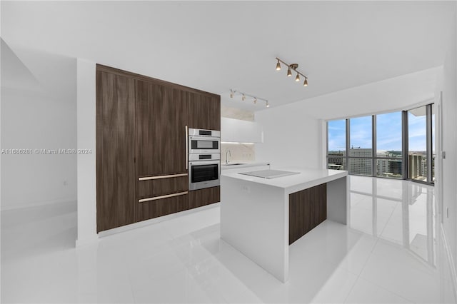 kitchen featuring black electric stovetop, sink, light tile patterned floors, a center island, and white cabinetry