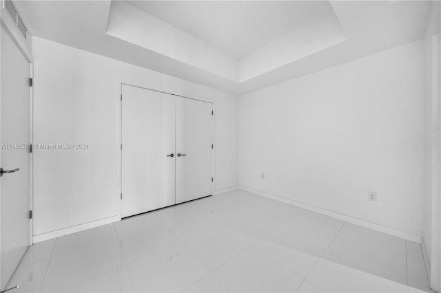 unfurnished bedroom featuring a tray ceiling and a closet