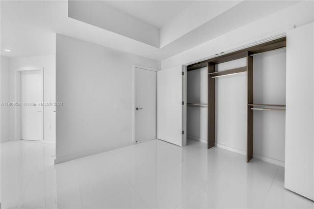 unfurnished bedroom featuring light tile patterned floors and a closet