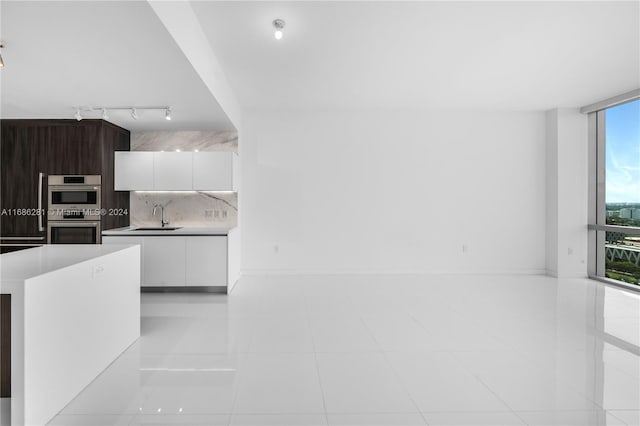 kitchen featuring dark brown cabinetry, white cabinetry, sink, double oven, and decorative backsplash