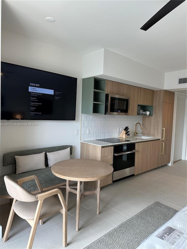 kitchen featuring stainless steel appliances, light tile patterned flooring, sink, and backsplash