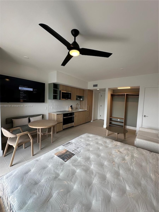 bedroom with ceiling fan, sink, and a closet