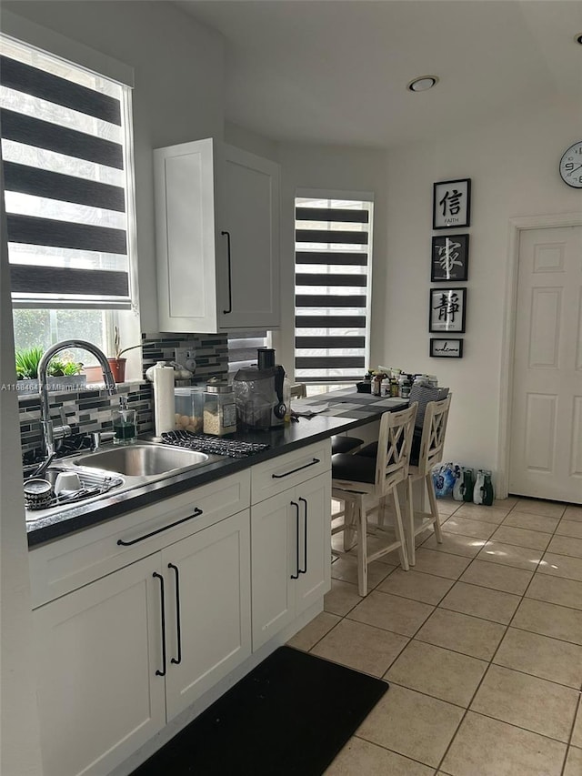 kitchen with white cabinetry, light tile patterned flooring, decorative backsplash, and sink