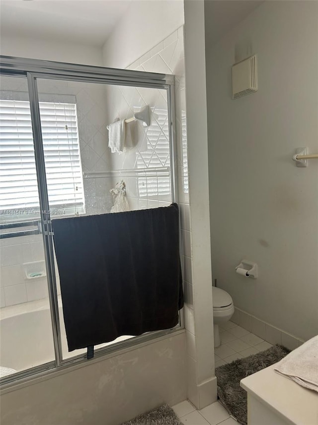 bathroom with tile patterned floors, shower / bath combination with glass door, and toilet