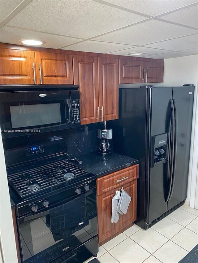 kitchen with light tile patterned flooring, a paneled ceiling, and black appliances