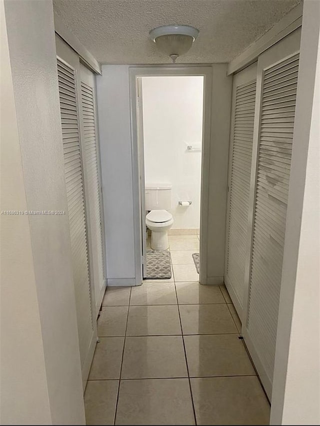 hallway featuring a textured ceiling and light tile patterned flooring