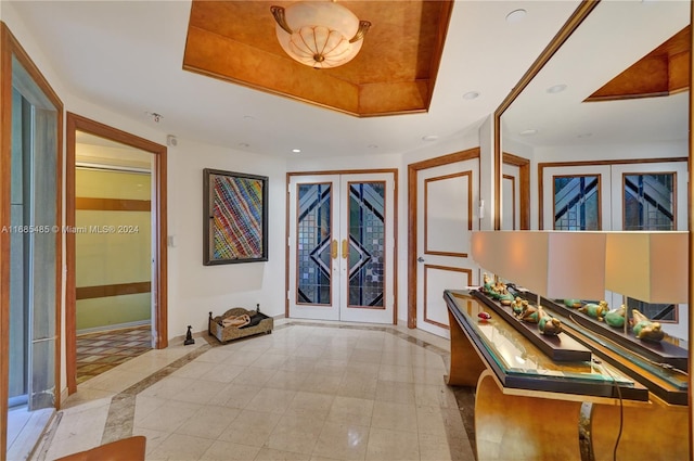 entrance foyer featuring french doors and a raised ceiling