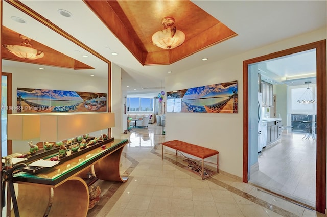 hall featuring a tray ceiling and light wood-type flooring