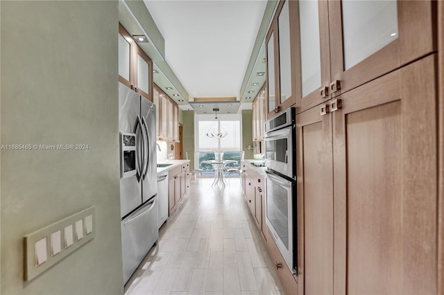 kitchen with stainless steel appliances, expansive windows, a chandelier, and hanging light fixtures