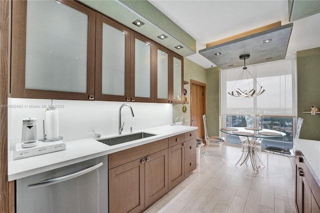 kitchen with sink, hanging light fixtures, light hardwood / wood-style floors, stainless steel dishwasher, and an inviting chandelier