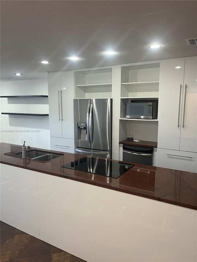 kitchen with dark tile patterned flooring, sink, stainless steel appliances, dark stone counters, and white cabinets