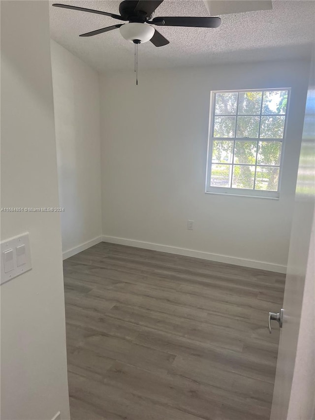 empty room featuring dark wood-type flooring, a textured ceiling, and ceiling fan