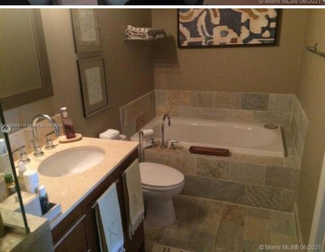 bathroom with vanity, toilet, and tiled tub