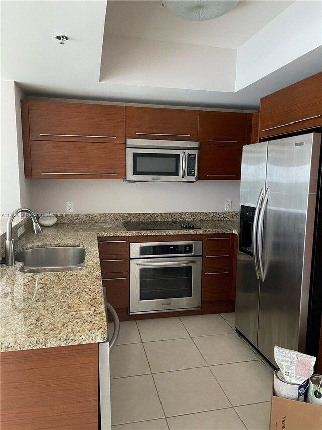 kitchen featuring light tile patterned floors, stainless steel appliances, sink, and a raised ceiling