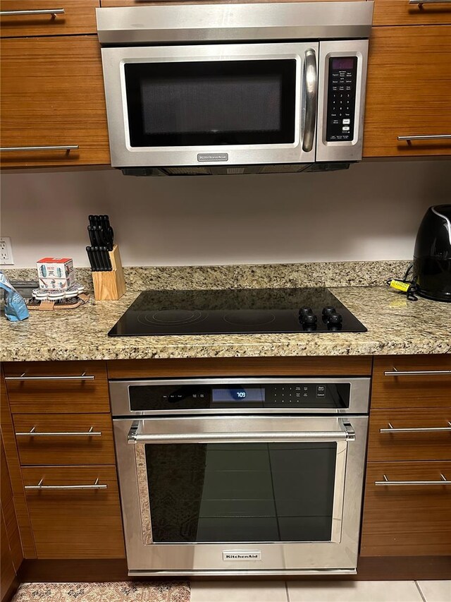 kitchen with light stone counters, stainless steel appliances, and light tile patterned floors