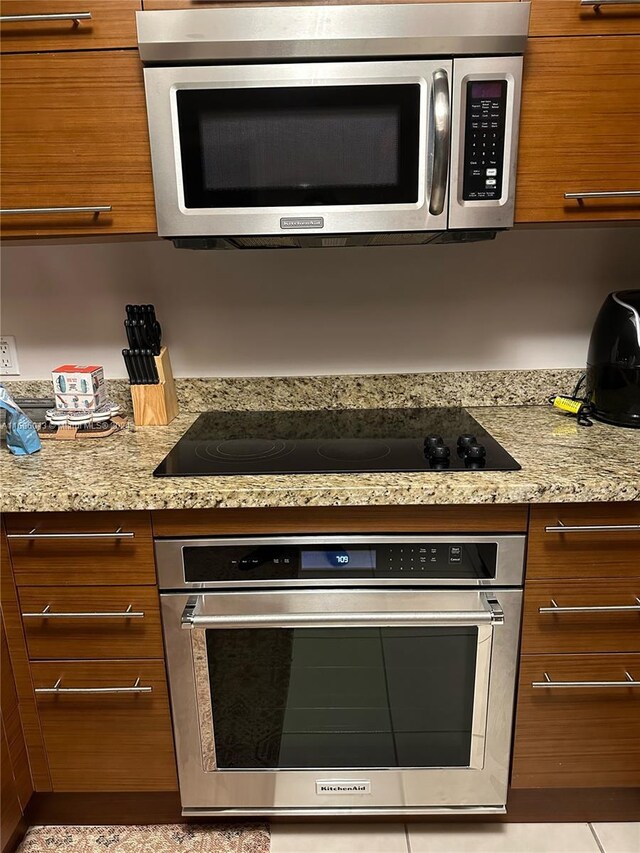 2641 N Flamingo Rd Unit 802N, Sunrise, FL 33323 - kitchen featuring appliances with stainless steel finishes, brown cabinetry, and light stone countertops