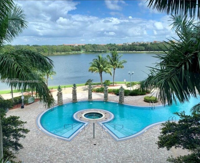 view of pool featuring a patio area, a hot tub, and a water view