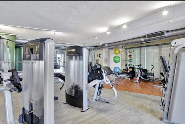 gym with a textured ceiling and wood-type flooring