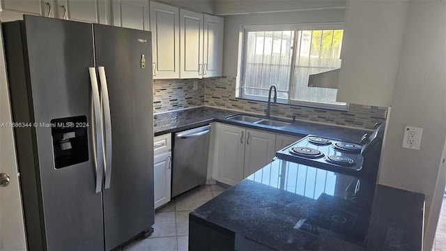 kitchen with decorative backsplash, stainless steel appliances, sink, light tile patterned floors, and white cabinets