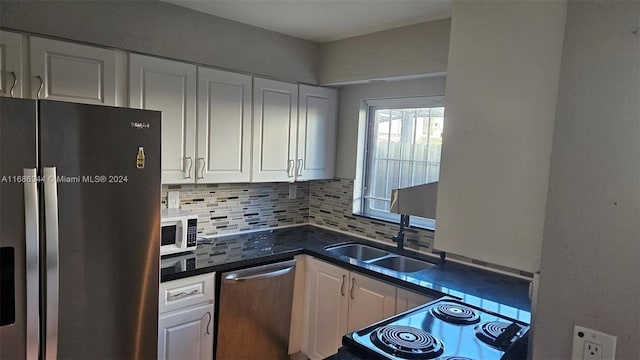 kitchen with white cabinetry, backsplash, stainless steel appliances, and sink