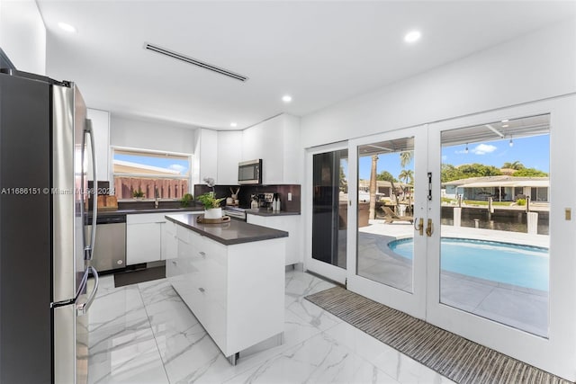 kitchen featuring appliances with stainless steel finishes, french doors, white cabinets, and a healthy amount of sunlight