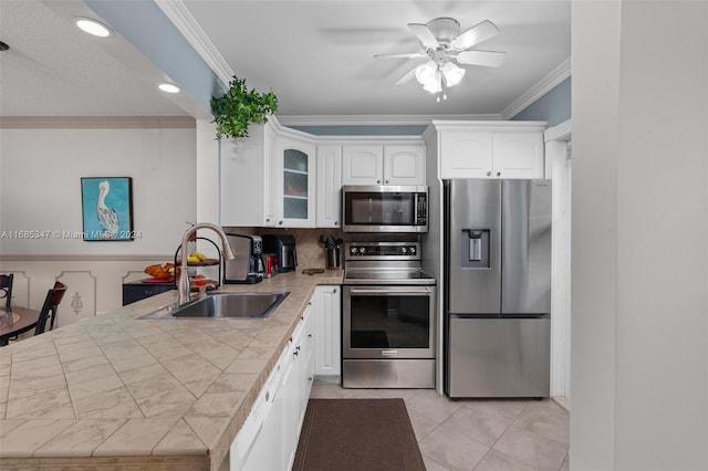 kitchen with stainless steel appliances, crown molding, sink, white cabinets, and ceiling fan