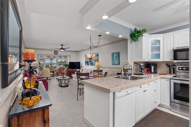 kitchen featuring kitchen peninsula, white cabinetry, ornamental molding, sink, and stainless steel appliances