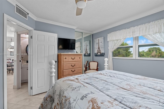 tiled bedroom with ornamental molding, a closet, a textured ceiling, and ceiling fan