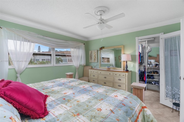 tiled bedroom featuring a closet, ornamental molding, a textured ceiling, and ceiling fan