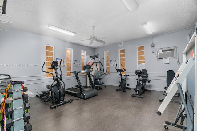 gym with a wall unit AC, a textured ceiling, hardwood / wood-style floors, and ceiling fan