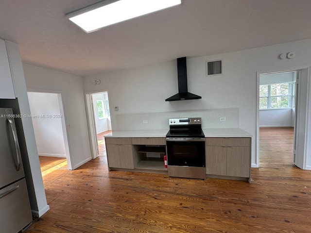 kitchen with wall chimney range hood, stainless steel appliances, plenty of natural light, and dark hardwood / wood-style flooring