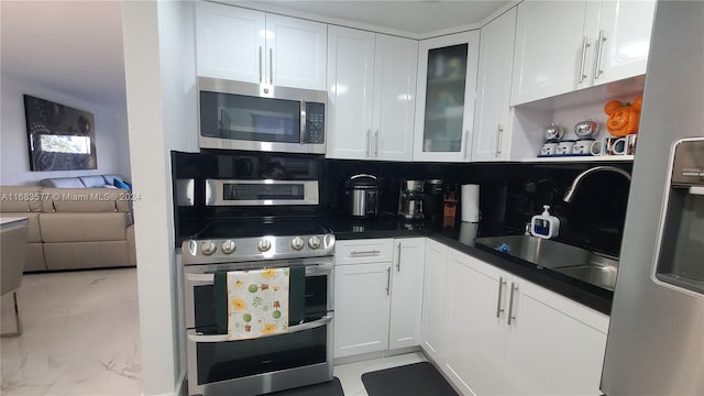 kitchen featuring decorative backsplash, white cabinetry, and stainless steel appliances