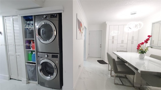 clothes washing area with ornamental molding and stacked washing maching and dryer