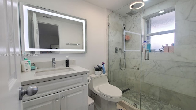 bathroom featuring vanity, a shower with shower door, and toilet