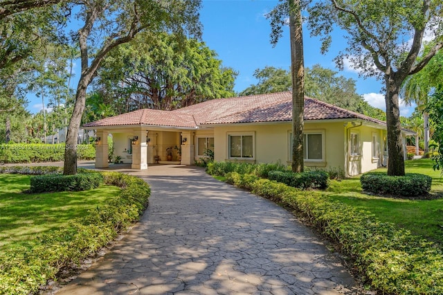 single story home with stucco siding, driveway, a tile roof, and a front yard