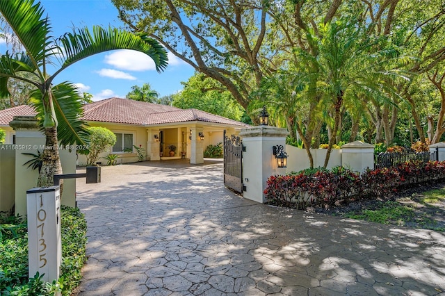 view of front facade featuring a fenced front yard, stucco siding, a gate, a tiled roof, and driveway
