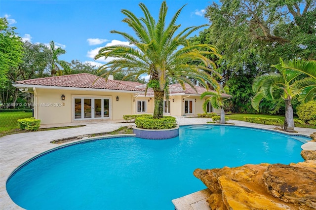 pool with fence, french doors, and a patio area