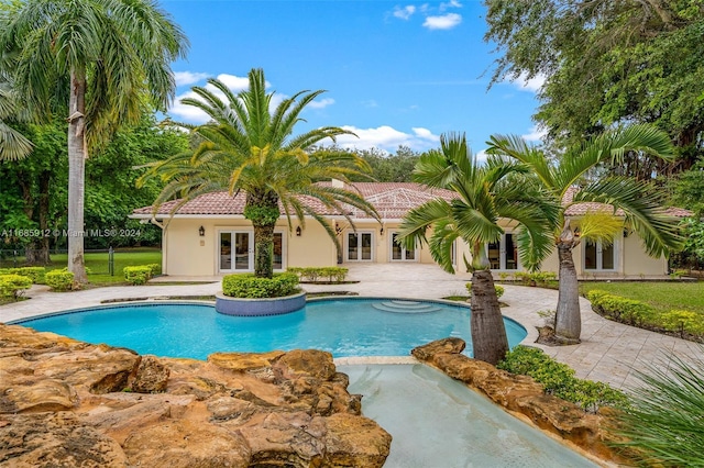 outdoor pool with a patio area and french doors
