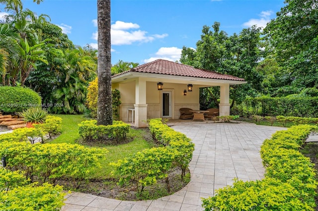 view of front of property with a tiled roof, a patio area, and stucco siding