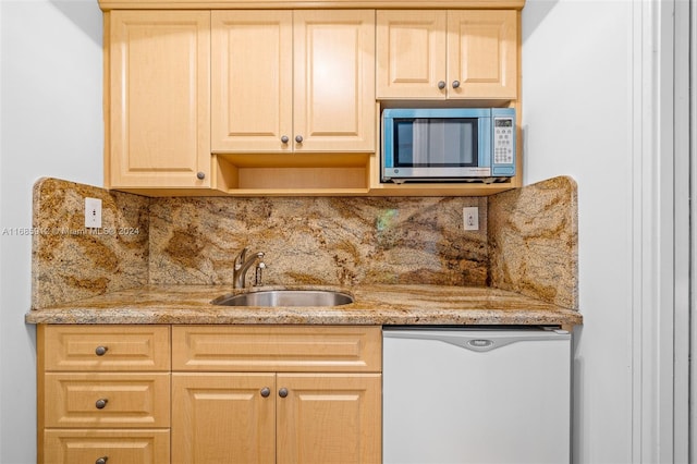 kitchen with light brown cabinets, refrigerator, stainless steel microwave, a sink, and backsplash
