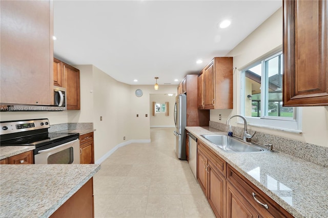 kitchen with light stone countertops, light tile patterned flooring, appliances with stainless steel finishes, and sink