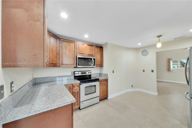 kitchen featuring appliances with stainless steel finishes, light tile patterned flooring, decorative light fixtures, and light stone counters