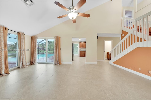 unfurnished living room with light tile patterned floors, high vaulted ceiling, and ceiling fan