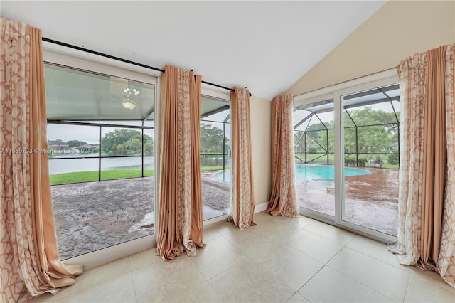 doorway to outside featuring a water view, light tile patterned floors, lofted ceiling, and plenty of natural light