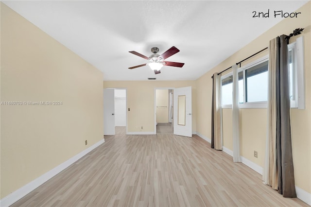 unfurnished bedroom with light hardwood / wood-style flooring, a spacious closet, and ceiling fan