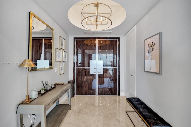 doorway featuring a chandelier, a tray ceiling, and concrete floors